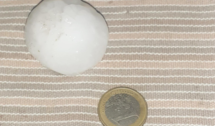 Una de las pelotas de granizo junto a un euro