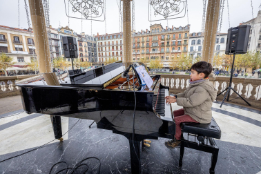Fotos de personas tocando el piano de cola instalado en el kiosco de la Plaza del Castillo de Pamplona. /