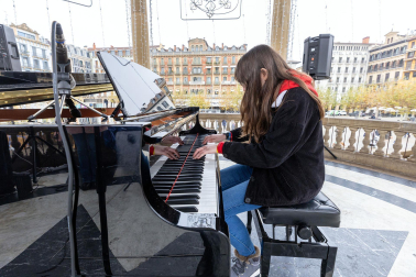 Fotos de personas tocando el piano de cola instalado en el kiosco de la Plaza del Castillo de Pamplona. /