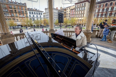 Fotos de personas tocando el piano de cola instalado en el kiosco de la Plaza del Castillo de Pamplona. /