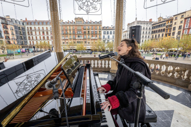 Fotos de personas tocando el piano de cola instalado en el kiosco de la Plaza del Castillo de Pamplona. /