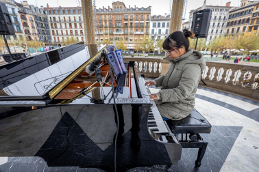 Fotos de personas tocando el piano de cola instalado en el kiosco de la Plaza del Castillo de Pamplona. /