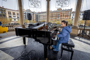 Fotos de personas tocando el piano de cola instalado en el kiosco de la Plaza del Castillo de Pamplona. /