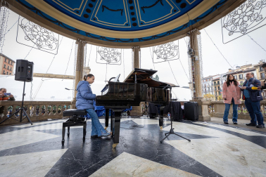 Fotos de personas tocando el piano de cola instalado en el kiosco de la Plaza del Castillo de Pamplona. /