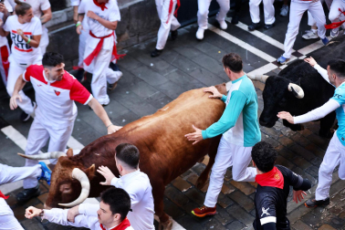 La manada de La Palmosilla, rodeada de mozos en el tramo de la Estafeta durante el `primer encierro de los Sanfermines 2024
