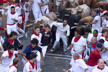 Los mozos corren junto a los morlacos de La Palmosilla en el tramo de la Plaza del Ayuntamiento durante el primer encierro de los Sanfermines 2024