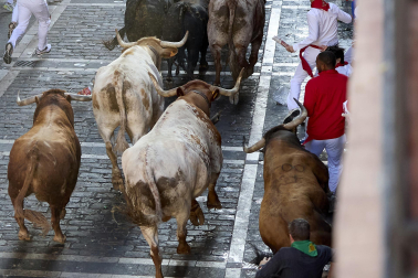 Los mozos corren junto a los morlacos de La Palmosilla en el tramo de la Plaza del Ayuntamiento durante el primer encierro de los Sanfermines 2024