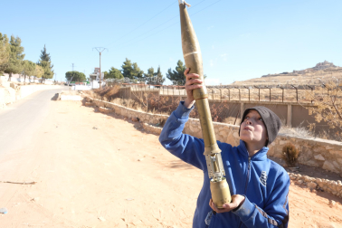 Un niño juega con un proyectil a la entrada de la prisión de Saydnaya.