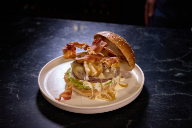 Diseñada por los cocineros de Gastro Okei Errialde, Errialde Team. Carne acompañada de una salsa de guacamole, mayonesa de lima, queso gouda, cebolla caramelizada, plátano frito, salsa de jagger y panceta crujiente
