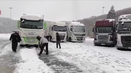 Los camioneros atrapados en la estación de servicio de Pagozelai retiran con unas palas la nieve acumulada bajo sus vehículos para poder moverlos.