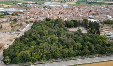 Imagen aérea del parque municipal de Cortes, con la plaza para actos en su interior y, al fondo, el castillo y núcleo urbano de la localidad ribera