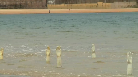 Vídeo de la colocación de la instalación 'EskuBideak',  con cientos de moldes de guantes en la playa de La Concha