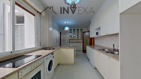 Cocina con mobiliario a ambos lados y ventana a uno de los patios
