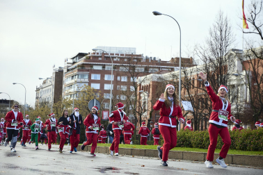 Participantes de todas las edades recorren el centro de Madrid vestidos de papá noeles durante la 14ª edición de la Carrera de Papá Noel, este domingo 21 de diciembre