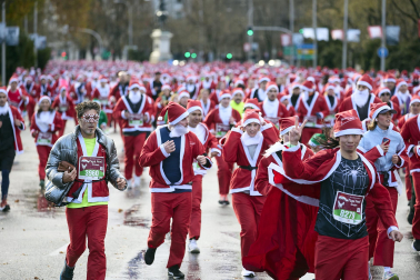 Participantes de todas las edades recorren el centro de Madrid vestidos de papá noeles durante la 14ª edición de la Carrera de Papá Noel, este domingo 21 de diciembre