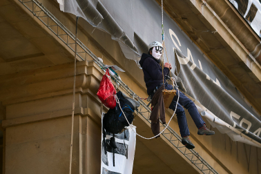 Dos personas con casco y mascarilla han desplegado este viernes por la mañana tres pancartas en la fachada principal del edificio de exposiciones de la Plaza de la Libertad de Pamplona.