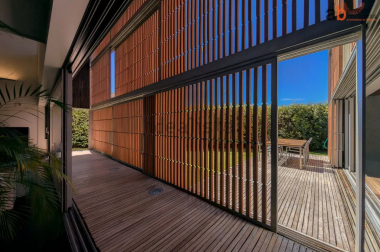 Pasillo con correderas y celosías que permiten conectar la vivienda con el jardín