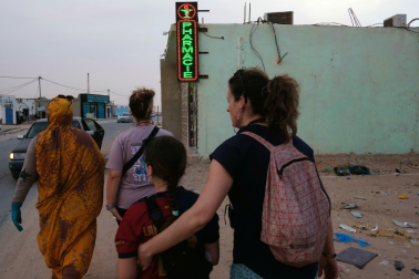 Marta, Helena, Laura y Lala caminan por delante de una de las cuatro farmacias abiertas en la parte trasera del hospital de El Aaiún.