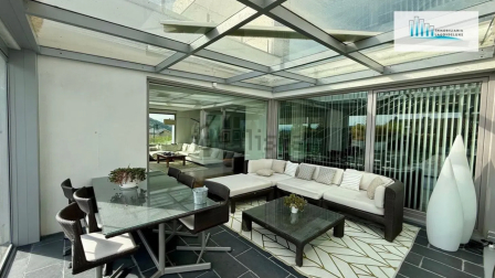Porche con techo acristalado y cortinas de cristal para que pueda abrirse al jardín los días de buen tiempo