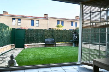 Vista del jardín desde el porche, cuya cristalera se abre completamente para permitir una continuidad con la zona verde