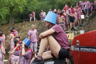 HARO (ESPAÑA), 29/06/2026.- Un chica con un cubo en la cabeza descansa durante la batalla del Vino de Haro, Fiesta de Interés Turístico Nacional, este lunes en la que sus participantes se lanzan unos a otros litros de vino sin descanso en un impresionante espectáculo, que concluye al mediodía, y que en 2025, al ser domingo, congregó a cerca de 10.000 personas, que tiñeron de morado el paraje de los Riscos de Bilibio con unos 40.000 litros de vino. EFE/ Villar López