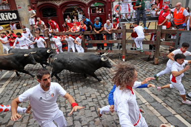 Fotos del séptimo encierro de San Fermín 2026 con toros de Miura en la curva de Mercaderes.