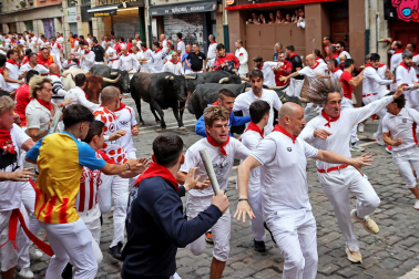 Fotos del séptimo encierro de San Fermín 2026 con toros de Miura en la curva de Mercaderes.
