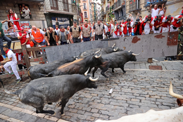 Fotos del séptimo encierro de San Fermín 2026 con toros de Miura en la curva de Mercaderes.