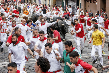 Fotos del séptimo encierro de San Fermín 2026 con toros de Miura en la curva de Mercaderes.