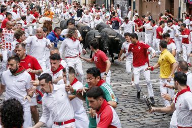Fotos del séptimo encierro de San Fermín 2026 con toros de Miura en la curva de Mercaderes.