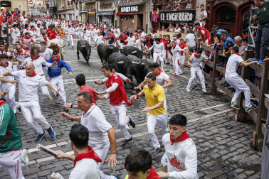 Fotos del séptimo encierro de San Fermín 2026 con toros de Miura en la curva de Mercaderes.