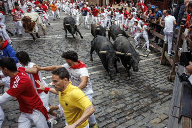 Fotos del séptimo encierro de San Fermín 2026 con toros de Miura en la curva de Mercaderes.