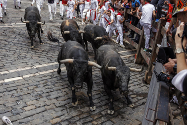 Fotos del séptimo encierro de San Fermín 2026 con toros de Miura en la curva de Mercaderes.