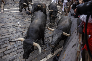 Fotos del séptimo encierro de San Fermín 2026 con toros de Miura en la curva de Mercaderes.