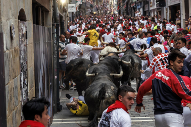 Fotos del séptimo encierro de San Fermín 2026 con toros de Miura en la curva de Mercaderes.