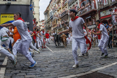 Fotos del séptimo encierro de San Fermín 2026 con toros de Miura en la curva de Mercaderes.