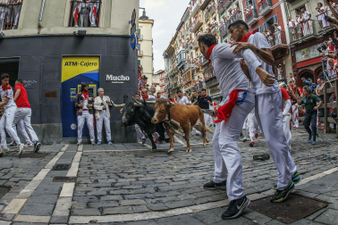 Fotos del séptimo encierro de San Fermín 2026 con toros de Miura en la curva de Mercaderes.