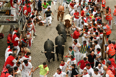Fotos del séptimo encierro de San Fermín 2026 con toros de Miura en la bajada al callejón.