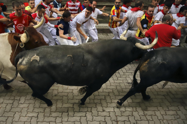 Fotos del séptimo encierro de San Fermín 2026 con toros de Miura en la bajada al callejón.