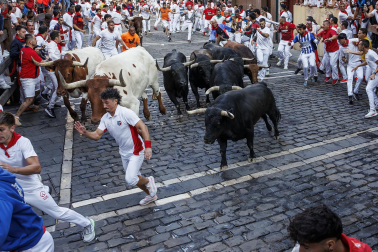 Fotos del octavo encierro de San Fermín 2026 con toros de la ganadería de Jandilla en la curva de Mercaderes.