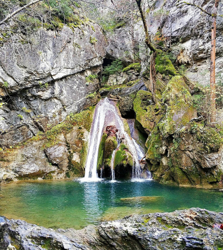 El caudal de la cascada de Belabarce cae por las rocas llenas de musgo y vegetación