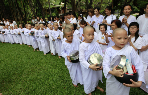 Monjas y novicias budistas rezando y pidiendo comida en Bangkok