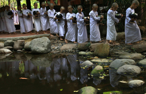 Monjas y novicias budistas rezando y pidiendo comida en Bangkok