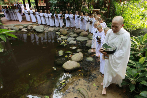 Monjas y novicias budistas rezando y pidiendo comida en Bangkok