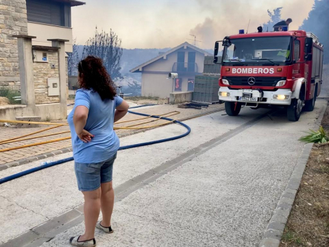 Fotos del incendio producido entre Obanos y Legarda. Una vecina observa como los bomberos intentan apagar el fuego de unas viviendas.