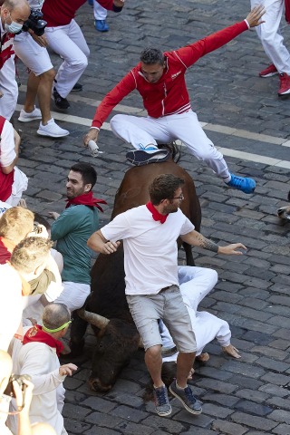 Un toro engancha a un mozo y lo arrastra en el callejón