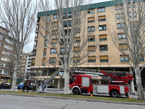 Bomberos de Navarra con un camión escala sofocan el incendio en una vivienda de la calle Iturrama de Pamplona.
