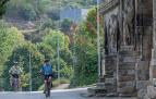 Dos personas acceden en bicicleta al entorno de Curtidores y contemplan la iglesia del Santo Sepulcro.