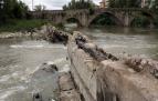 La presa de Santa Engracia con la escotadura central por donde se cuela el agua del río Arga desde hace más de dos años. Al fondo, el puente de Santa Engracia.