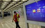Un operario de Iberia pasa al lado de un monitor con las banderas de España y Reino Unido en la T1 del Aeropuerto de Madrid-Barajas.